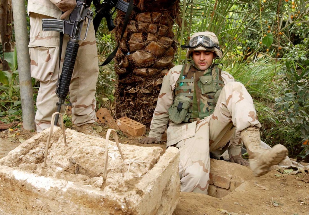 A U.S. soldier enters the "spider hole" where Saddam Hussein was captured.