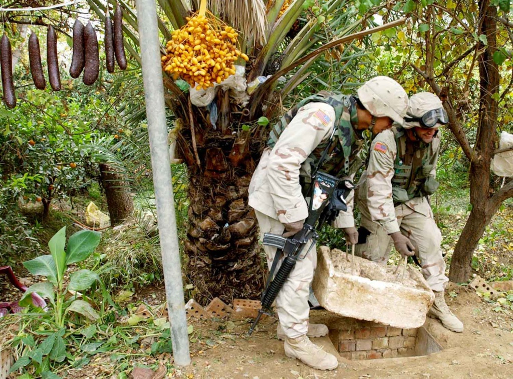 U.S. soldiers replace the styrofoam cover over the "spider hole" where Saddam Hussein was caught.