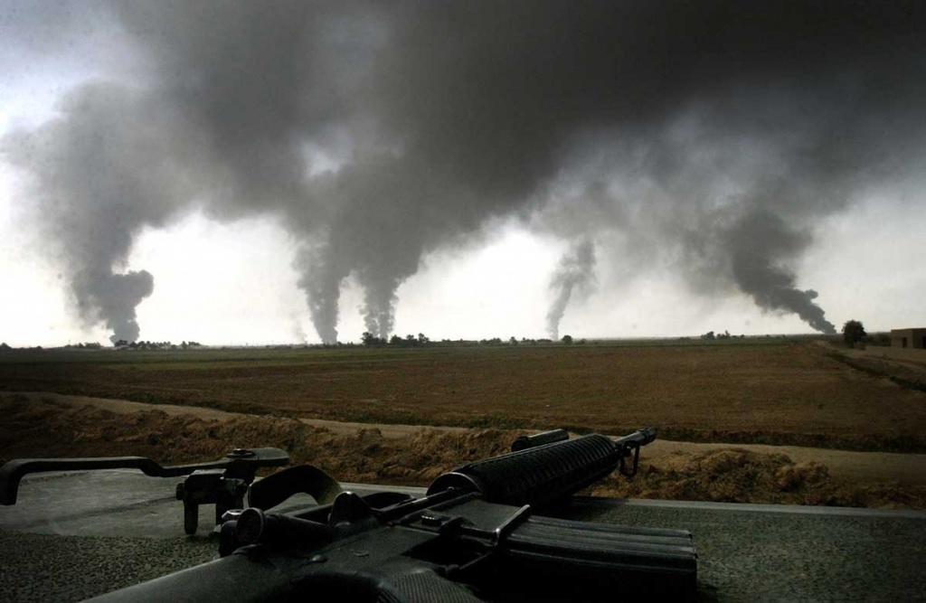 Marines of the Second Tank Battalion watch as oil fires darken the sky on the outskirts of Baghdad.