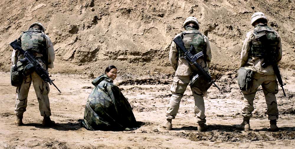 Honorary photo of the Poncho Queen, Cheryl Diaz Meyer, under a poncho, with Marines nearby.