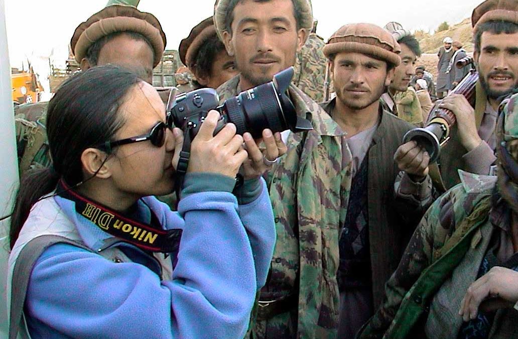 Female photographer surrounded by curious Afghan men