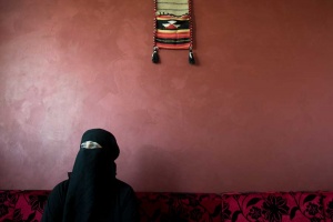 Iraqi prostitute covered in niqab against red wall