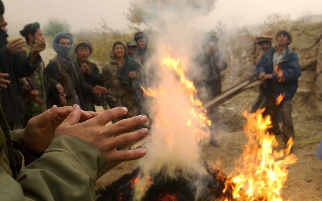 Mujaheddin fighters warm their hands with a bonfire