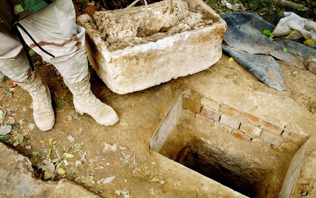 A brick-lined hole in the ground is shown open, a nearby styrofoam cover set aside, where deposed Iraqi President Saddam Hussein was caught in a hole on a farm house property in Al Dawr, near his hometown of Tikrit.