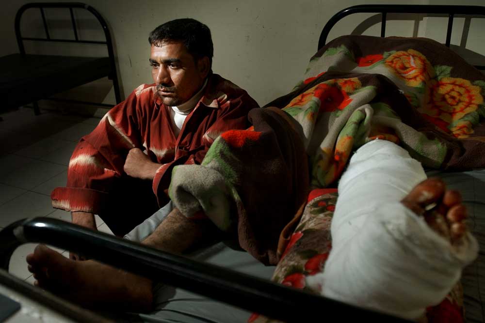 An Iraqi policeman watches over his cousin in a barebones hospital room.