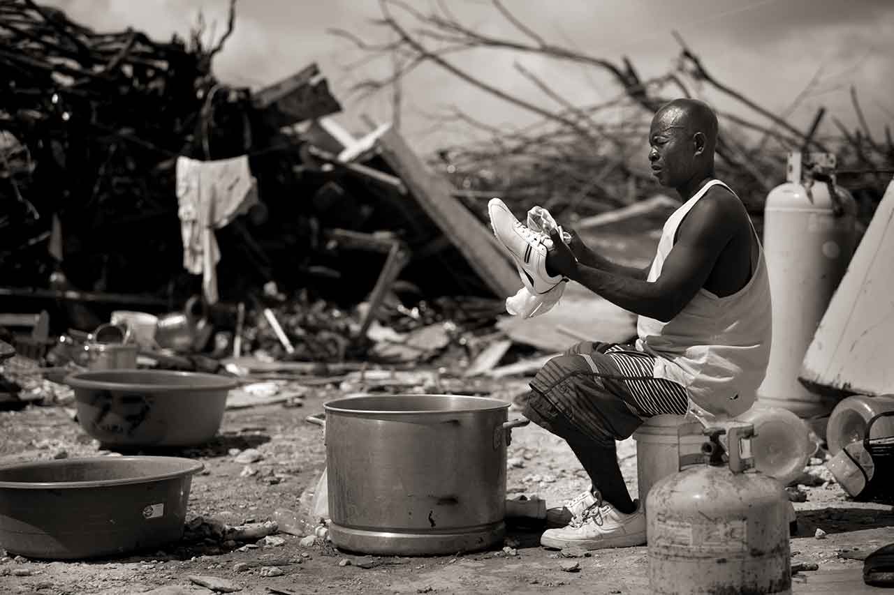 Haitian Manes Lundy wipes off a pair of brand new shoes that he procured after all his belongings were destroyed during Hurricane Dorian in the town of Marsh Harbour on Abaco in the Bahamas on Sept. 6, 2019. The Mudd, an immigrant shanty town, is home to about 8,000 Haitians, some of whom have lived in the area for several generations. "I have plenty of family dead here," said Lundy. That is the body of my cousin Doudoune Manes, but I don't have a way to bury her," he pointed to a visitor.