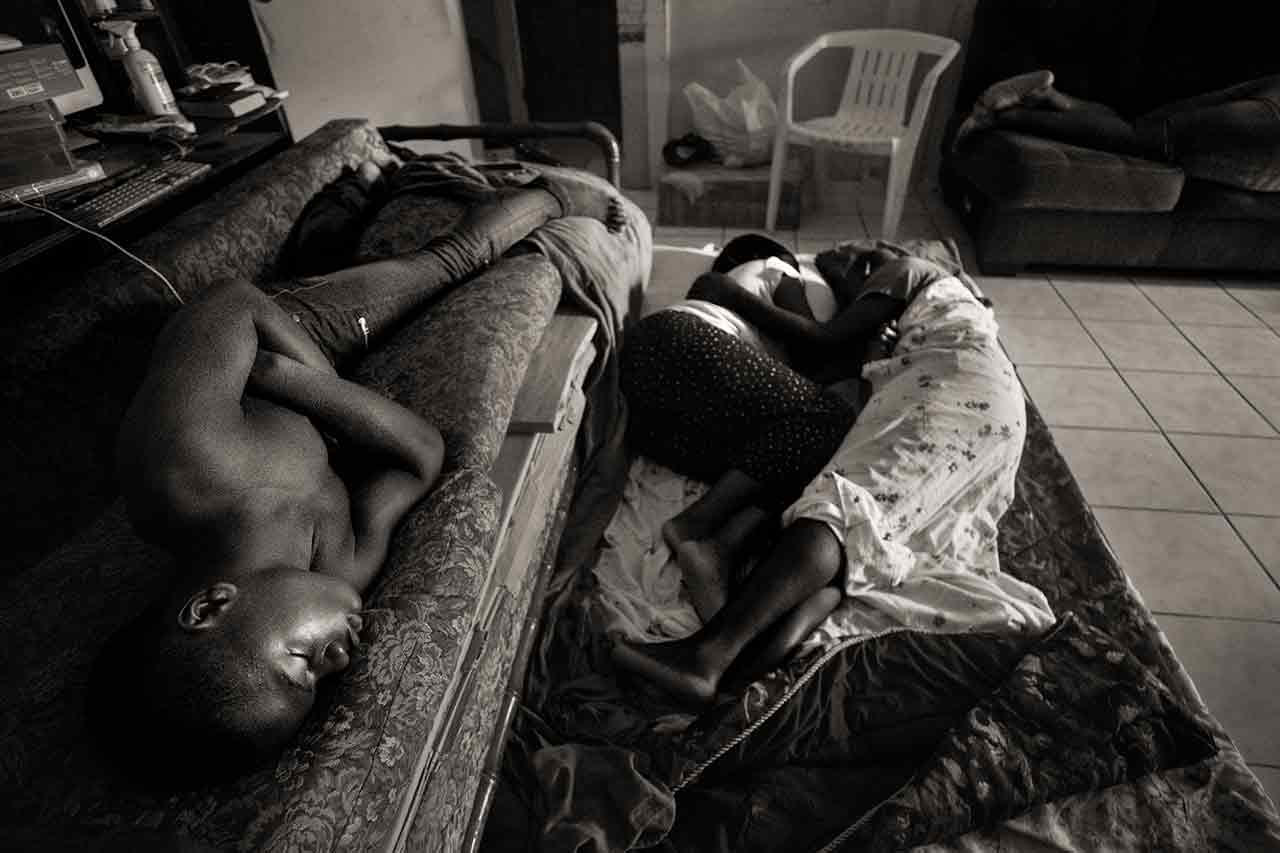 A month after Hurricane Dorian devastated the Bahamas, Abaco evacuees Justin Bain, 14, and his parents Sherrine Petit Homme LaFrance and Ferrier Petit Homme, left to right, sleep on available space in China Laguerre's home in Nassau, Bahamas, on Oct. 5, 2019. Laguerre's family took in 10 evacuees after the storm--housing, feeding and assisting them with their daily needs.