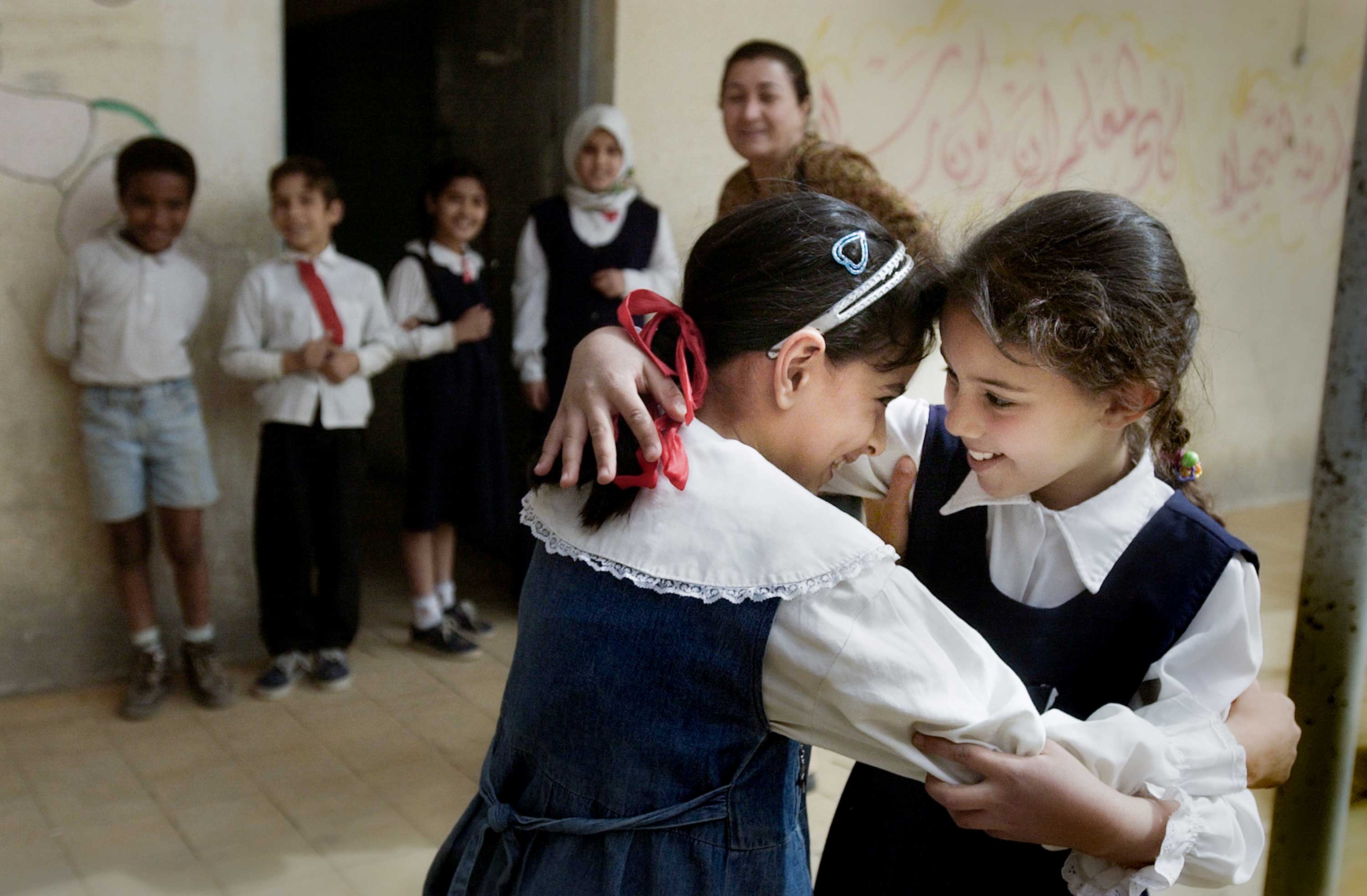 After not having seen each other for weeks during the war, Fatma Mohammad and Zubaida Salman, left and right, greet each other warmly at Al Amtithal Elementary School, the first to reopen in Baghdad, Iraq, after the U.S.-led invasion in 2003. Of 1200 pupils, only a handful of children returned after the school was cleared of munitions.