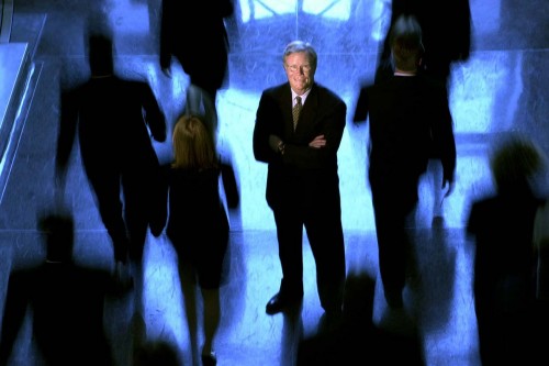 Portrait of former Dallas County District Attorney Bill Hill who oversaw some 210 prosecutors who prosecuted almost 96,000 cases annually in Texas. Portrait of an attorney in a suit with other lawyers in suits walking past him.