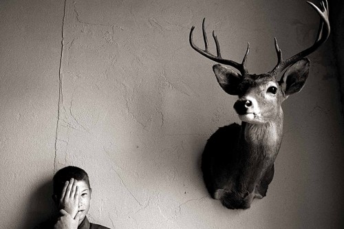 He shuffled around a north Texas law office where he worked quietly and no one spoke his name. He was the castaway of his family who abused him physically and sexually for years until finally Child Protective Services rescued him. Portrait of a boy covering half his face, next to a large deer head mounted on the wall.