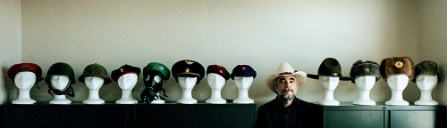 John Davidson, former Assistant Managing Editor of Visuals of The Dallas Morning News. Portait of man wearing a cowboy hat, framed by mannequins wearing military hats.