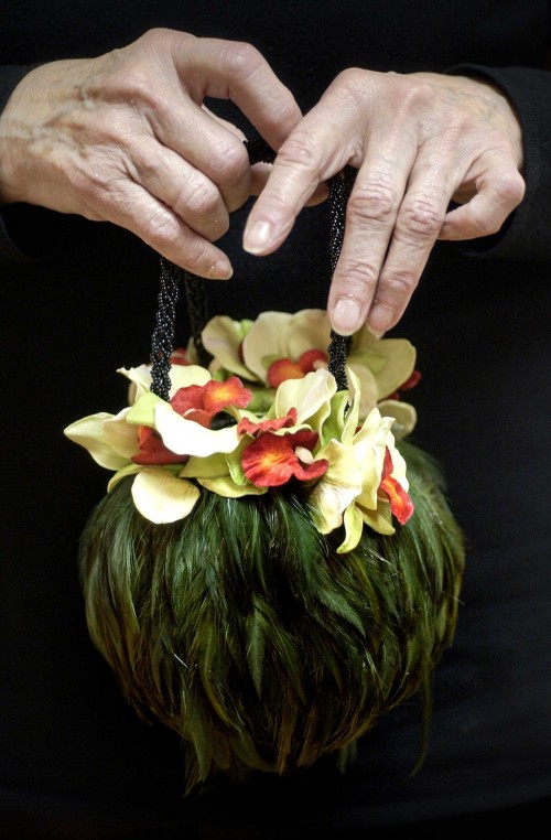 FashionCenterDallas, a new section in the World Trade Center, replaces the 40-year-old Apparel Mart and will be filled with one million square feet of clothing and accessories. A woman delicately holds an exquisite round bag covered in green feathers and topped with orchids.
